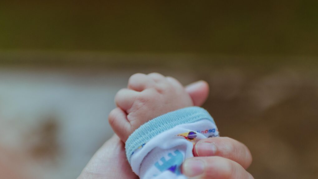 Voksen hånd som holder hånden til liten baby illustrasjonsfoto for prematurt født barn