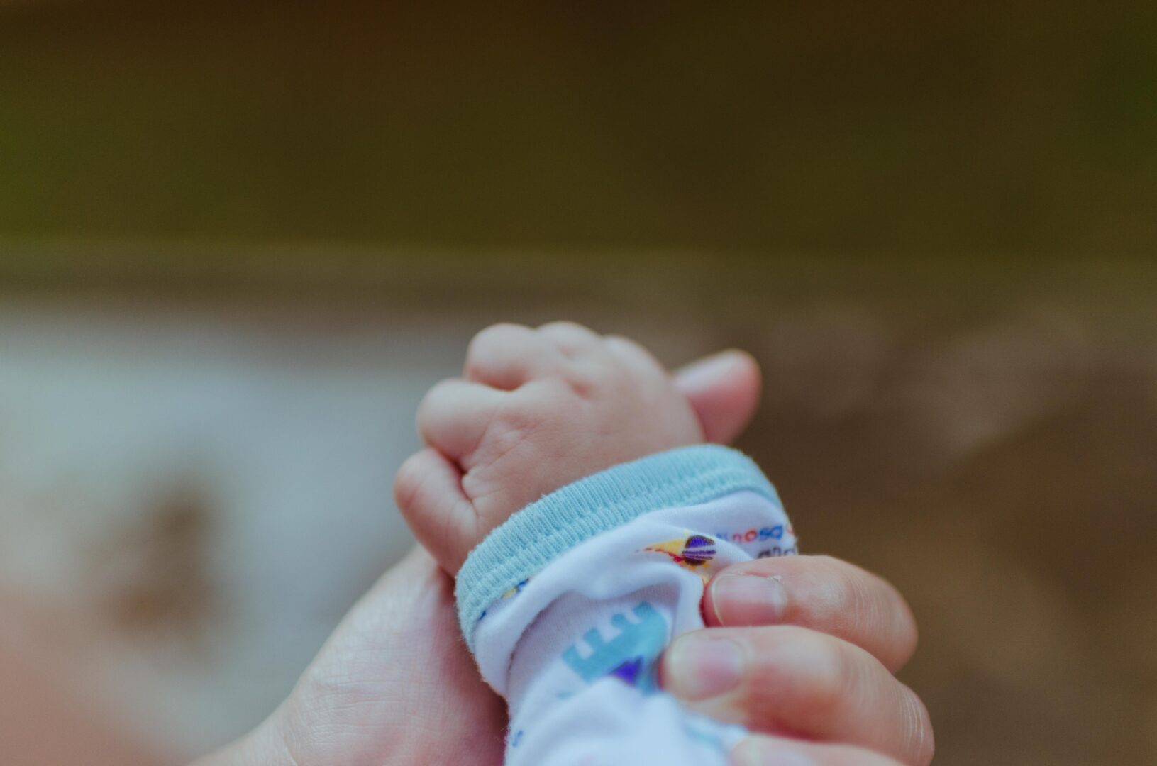 Voksen hånd som holder hånden til liten baby illustrasjonsfoto for prematurt født barn
